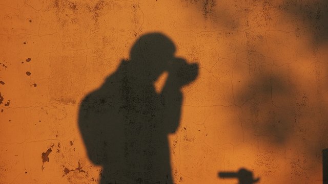 Shadow of male photographer taking pictures and checking captured shots on camera display.