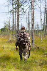 hunter walking in the swamp pine forest