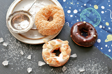 Donuts on stone board with sugar powder , crystals 