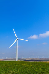 Wind turbine on the meadow on background of skies. 