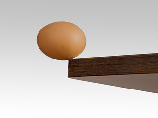 Egg teetering on the edge. Brink. Risk, danger concept or metaphor