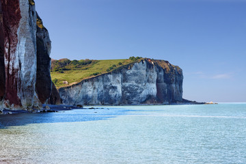 Cliffs at Normandy coast, Les Petites-Dalles, France. Blue beach lagoon with the white chalk cliffs...