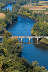 Obraz premium View over the Dordogne river seen from Domme village. The bridge over the river in Domme city. Medieval bridge crossing blue river in Perigord region. Bastide town in Dordogne, France.
