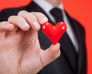 Young man holding a red heart on the palm
