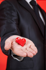 Young man holding a red heart on the palm