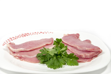 White dish with  raw pork loins and parsley, on white