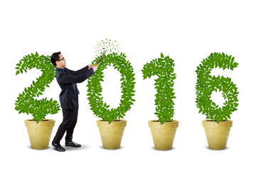 Businessman cutting the tree shaped numbers 2016