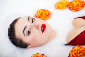 Obraz na płótnie Canvas Attractive girl enjoys a bath with milk and roses