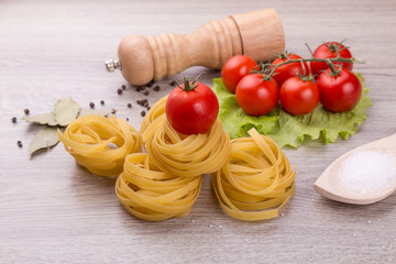 Pasta, tomatoes and pepper on a wooden background