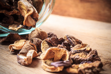 Dry mushrooms in jar on wooden table.