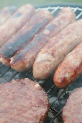 sausages and burgers cooking on barbecue