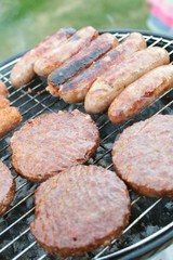 sausages and burgers cooking on barbecue