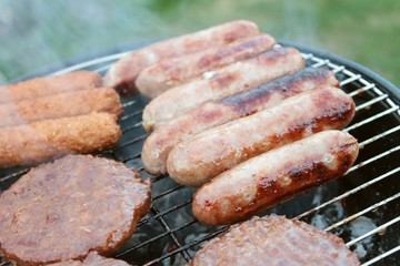 sausages and burgers cooking on barbecue