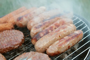 sausages and burgers cooking on barbecue