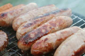 sausages and burgers cooking on barbecue