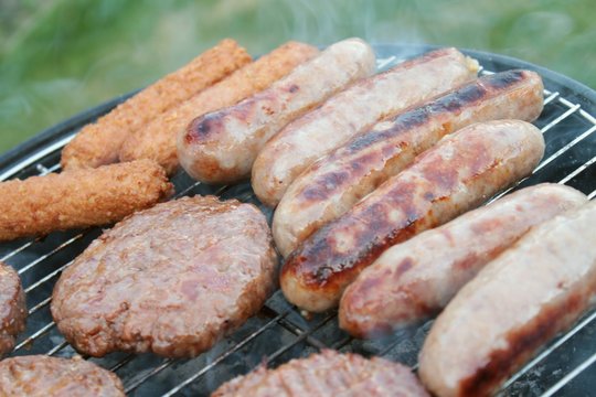 sausages and burgers cooking on barbecue