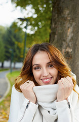 Portrait of cheerful young woman with autumn leafs in front of f