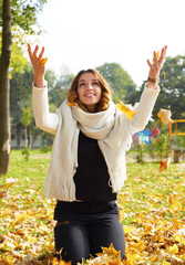 Fototapeta na wymiar Portrait of cheerful young woman with autumn leafs in front of f