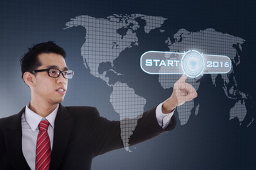 Worker pushing start button with numbers 2016