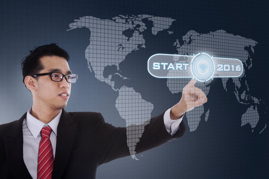 Worker pushing start button with numbers 2016