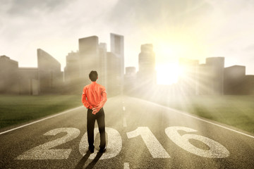 Young man standing on the road with numbers 2016