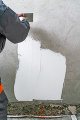 Construction worker - plastering and smoothing concrete wall wit