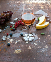 Glass of rose wine with berries, melon, grapes and ice on grunge rusty metal background
