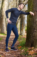 Runner doing stretching outside in autumn