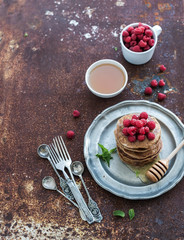 Breakfast set. Buckwheat pancakes with fresh raspberries, honey and mint leaves over grunge metal background