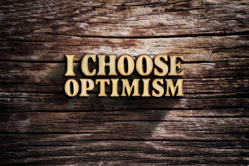 I choose Optimism. Words on old wooden board.