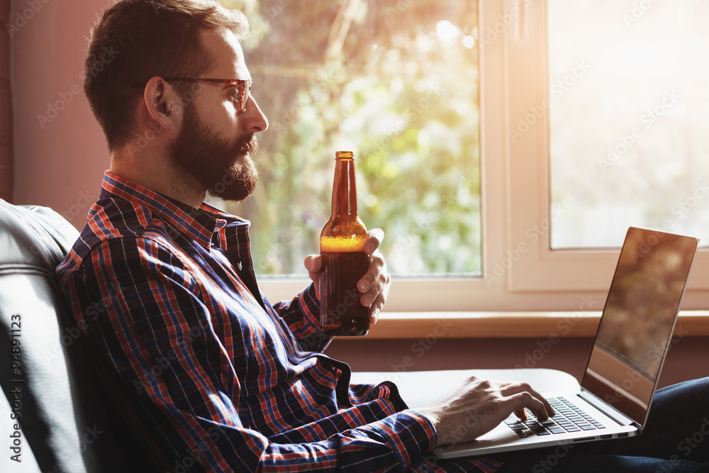 Wall mural bearded man with laptop drinking bottle of beer