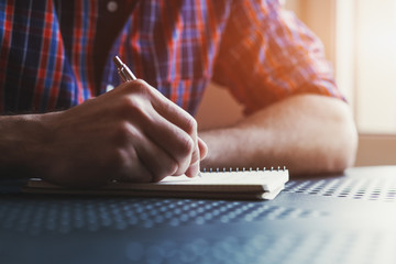 male hand writing in notebook with pen