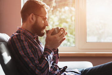 bearded man sitting with cup of morning coffee or tea