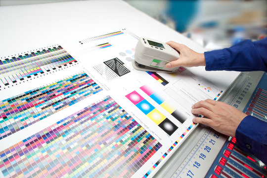 オフセット印刷色見台で測色する作業者の手