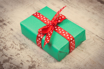 Obraz premium Vintage photo, Green gift for Christmas or other celebration on wooden plank