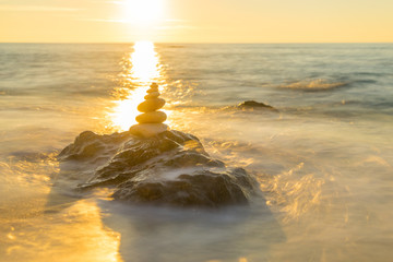 Stones pyramid on sand symbolizing zen, harmony, balance. Ocean