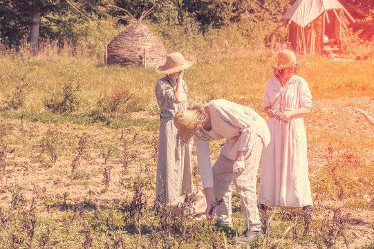 Group of people working in a field dressed in medieval white linen in Campus Galii in Messkirch