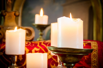 Dark artistic vintage edit of glowing lit church candles in the