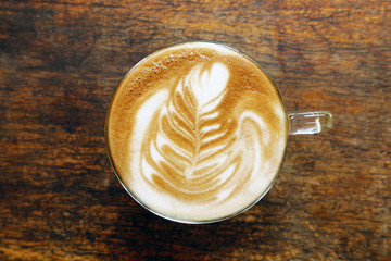 cup of latte art coffee on wooden background