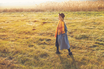 Romantic girl walking in a field in sunset light. Winter, autumn life