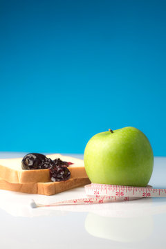 Measuring tape wrapped around a green apple with Slice of white