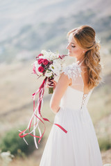 Beautiful young happy bride standing on the top of the mountain