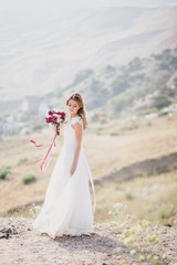 Fototapeta na wymiar Beautiful young happy bride standing on the top of the mountain