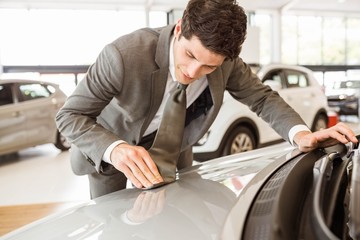 Focused businessman looking at the car body