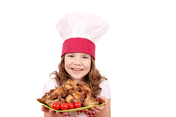 happy little girl cook with roasted chicken wings on plate