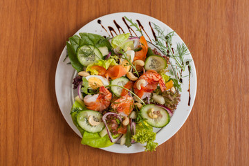 Colorful salad with shrimps on wooden table. Close up.