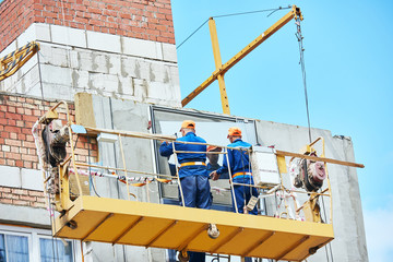 builders worker installing glass windows on facade