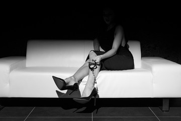 Sexy woman holding handcuffs on sofa black and white