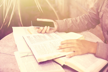 Girl with cell phone and books outdoor, instagram photo effect