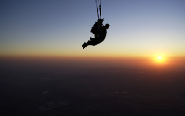 Skydivers open the parachute at the sunset